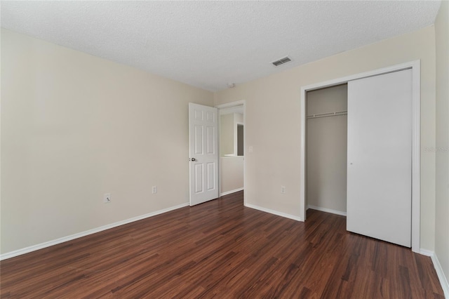 unfurnished bedroom with a closet, a textured ceiling, and dark hardwood / wood-style floors