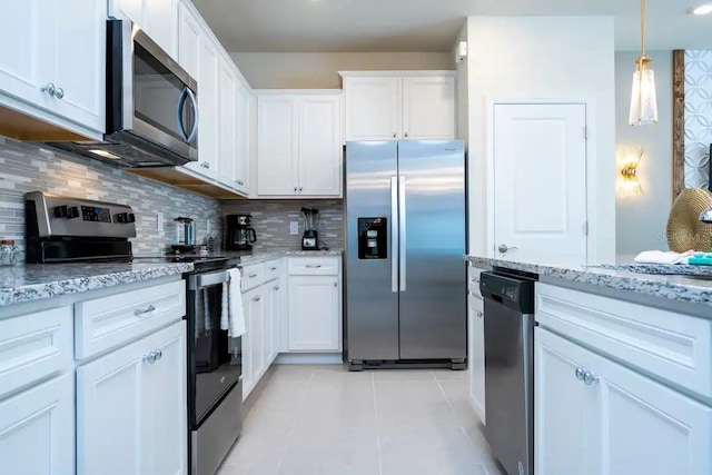 kitchen with stainless steel appliances, light stone countertops, and white cabinets