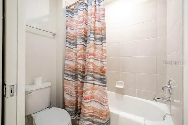 bathroom featuring toilet and shower / tub combo with curtain