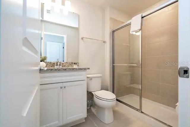 bathroom featuring vanity, toilet, and a shower with door