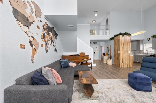 living room with sink, hardwood / wood-style floors, and a towering ceiling