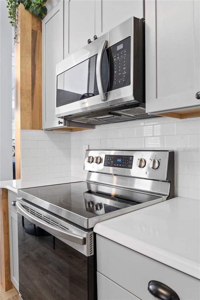 kitchen with backsplash, white cabinets, light hardwood / wood-style floors, and stainless steel appliances