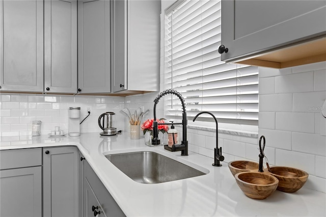 kitchen with gray cabinetry, sink, and backsplash