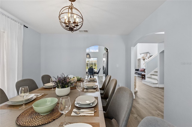 dining area with light wood-type flooring and an inviting chandelier