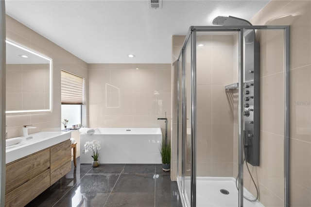 bathroom featuring tile walls, shower with separate bathtub, and vanity