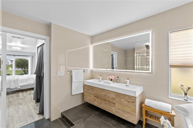 bathroom with hardwood / wood-style floors, a shower with door, vanity, and tile walls