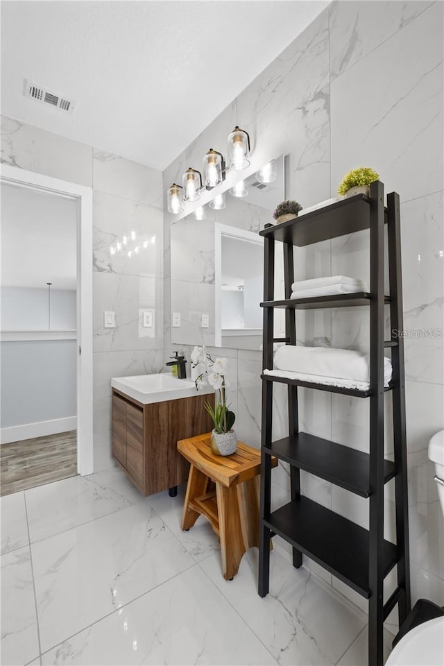 bathroom featuring vanity, toilet, and tile walls