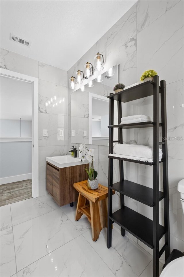 632 Pinewood Dr, Davenport, FL 33896 - bathroom with vanity, marble finish floors, toilet, and tile walls