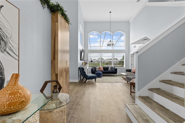 entrance foyer with a towering ceiling, wood-type flooring, and an inviting chandelier