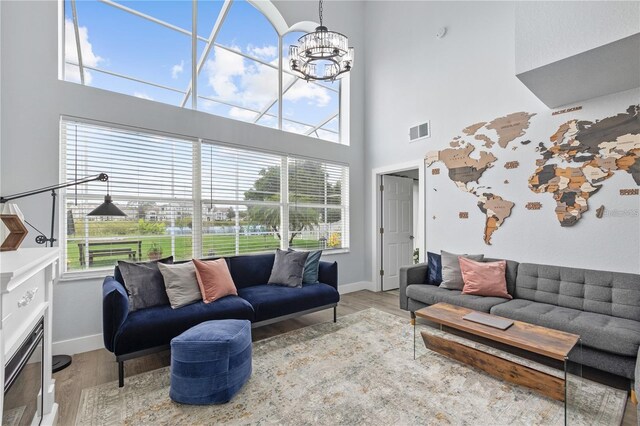 living room with a high ceiling, a chandelier, hardwood / wood-style flooring, and plenty of natural light