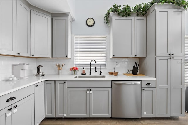 kitchen featuring light hardwood / wood-style floors, decorative backsplash, sink, gray cabinets, and stainless steel dishwasher