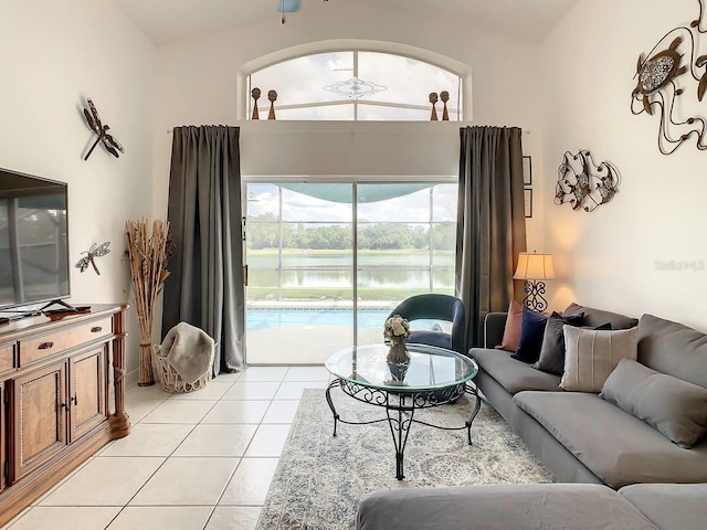 living room with ceiling fan, light tile patterned flooring, a water view, and vaulted ceiling