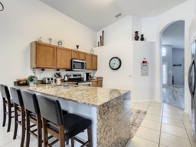 kitchen featuring a kitchen bar, kitchen peninsula, sink, and appliances with stainless steel finishes