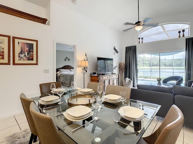 tiled dining space featuring ceiling fan and a high ceiling