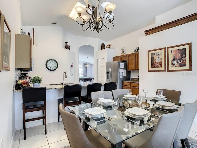 dining area with sink, an inviting chandelier, lofted ceiling, and light tile patterned flooring