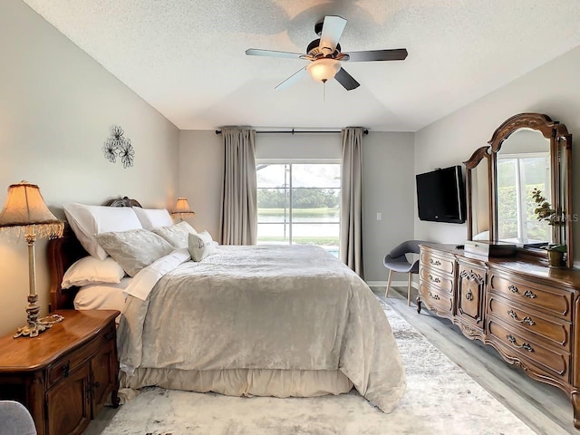 bedroom featuring ceiling fan, light hardwood / wood-style floors, and a textured ceiling