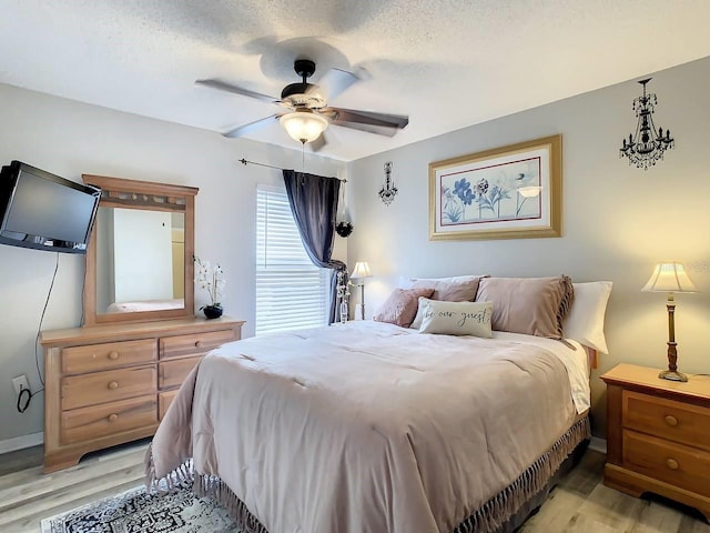 bedroom with a textured ceiling, light wood-type flooring, and ceiling fan