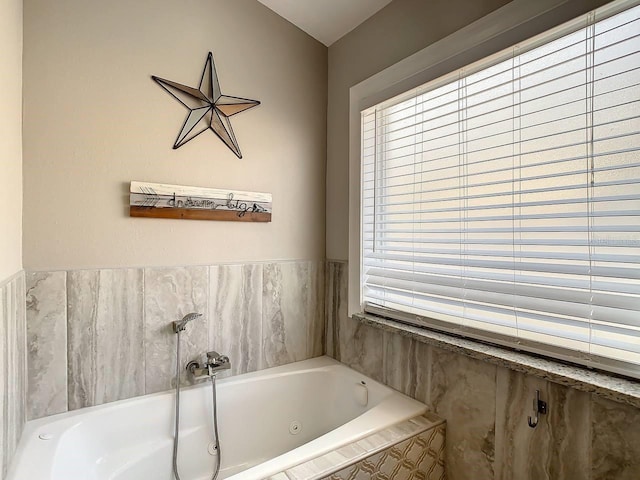 bathroom featuring a relaxing tiled tub and a healthy amount of sunlight