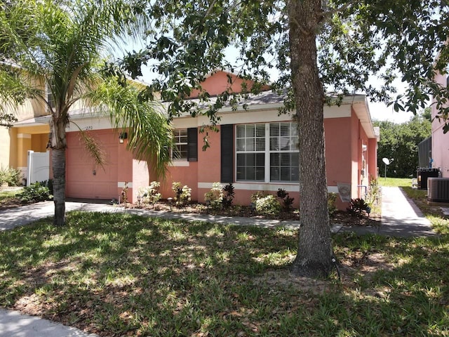 ranch-style house featuring a front yard, a garage, and cooling unit