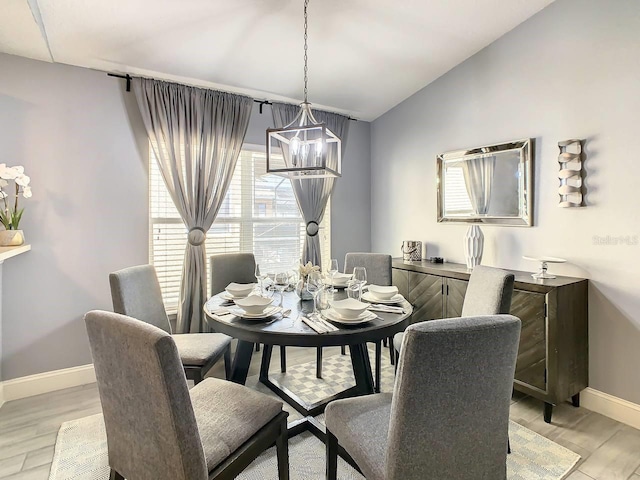 dining area with a wealth of natural light, light hardwood / wood-style flooring, lofted ceiling, and an inviting chandelier