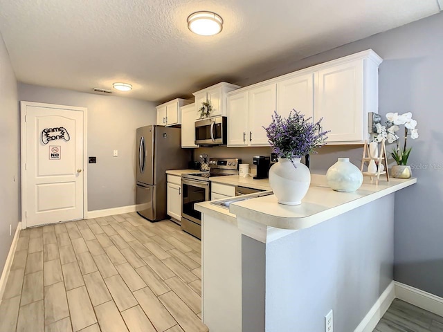 kitchen featuring stainless steel appliances, white cabinetry, light wood-type flooring, and kitchen peninsula