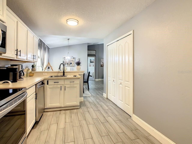 kitchen featuring white cabinetry, sink, decorative light fixtures, and vaulted ceiling