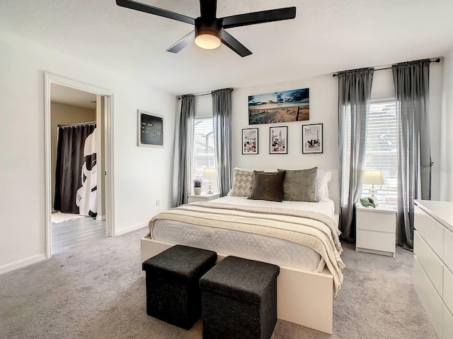 carpeted bedroom with a walk in closet, multiple windows, and ceiling fan