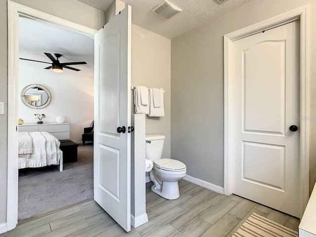 bathroom featuring toilet, a textured ceiling, hardwood / wood-style flooring, and ceiling fan