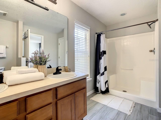 bathroom with a shower with curtain, vanity, a textured ceiling, and wood-type flooring