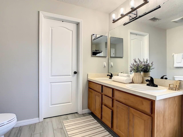 bathroom featuring toilet, vanity, and a textured ceiling