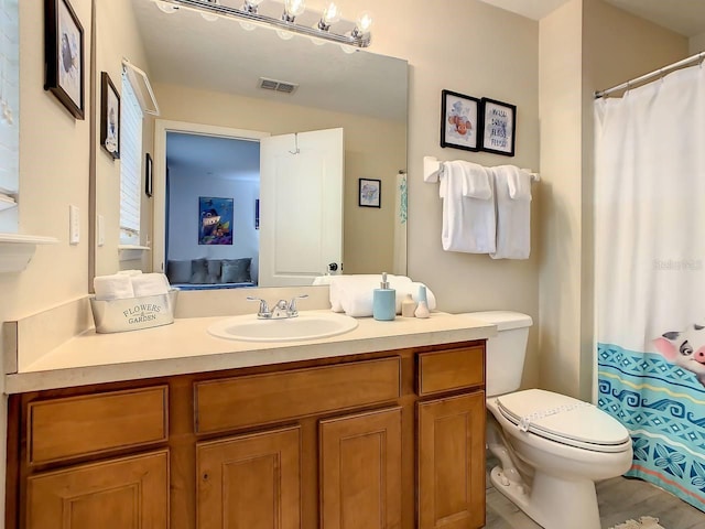 bathroom featuring toilet, vanity, and curtained shower