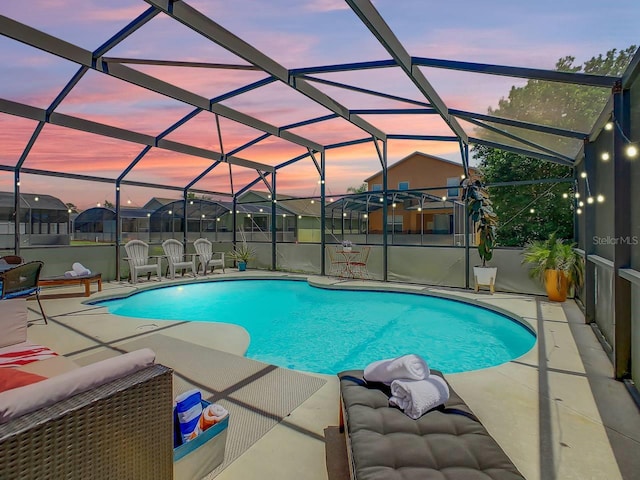 pool at dusk featuring glass enclosure and a patio area