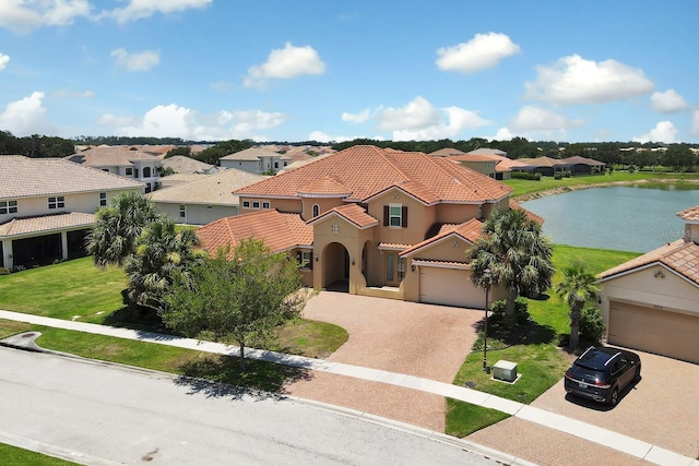 mediterranean / spanish-style home featuring a front lawn, a garage, and a water view