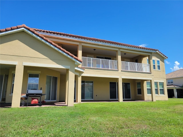 back of property with a lawn and a balcony