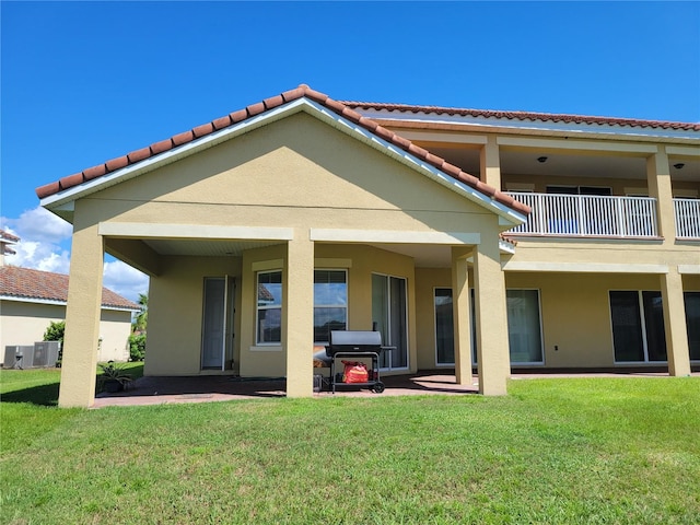 back of property with a lawn and a balcony