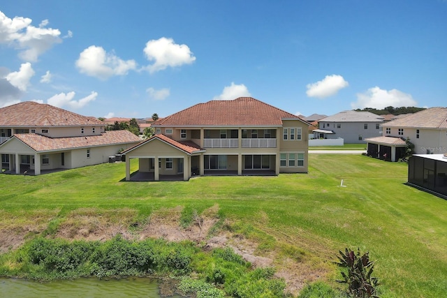 back of house with a lawn and a water view