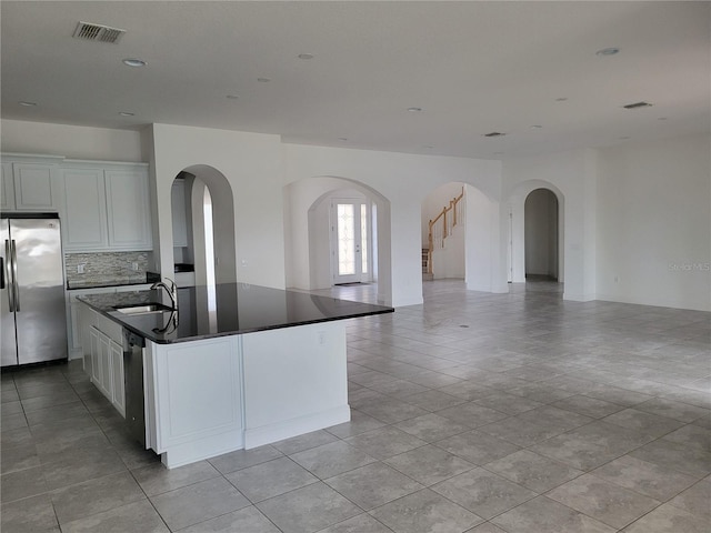 kitchen featuring white cabinetry, stainless steel appliances, sink, and an island with sink