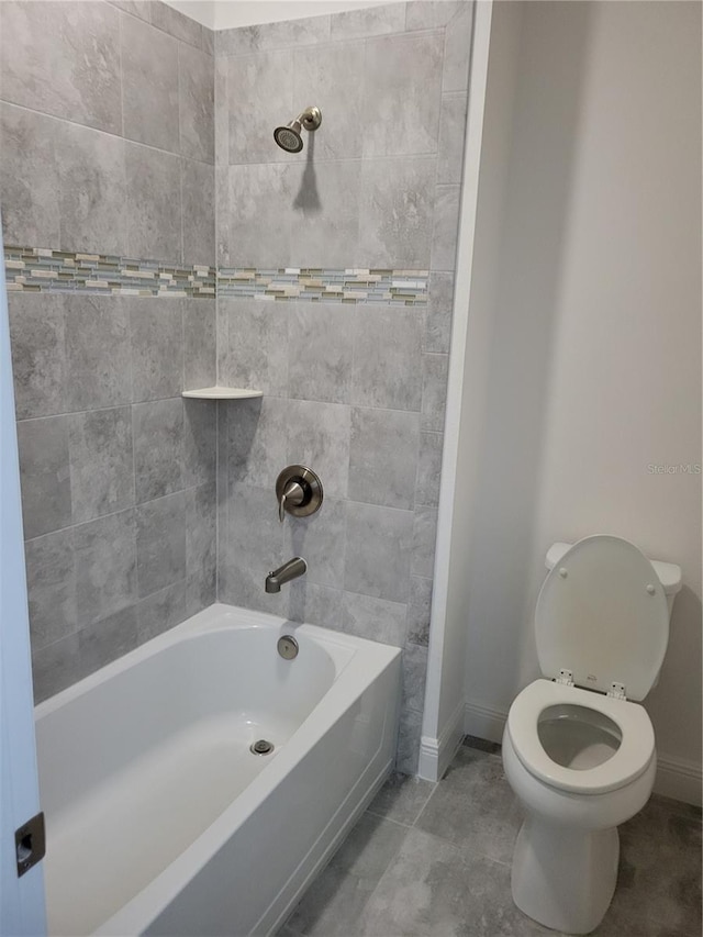 bathroom featuring tile patterned floors, tiled shower / bath, and toilet