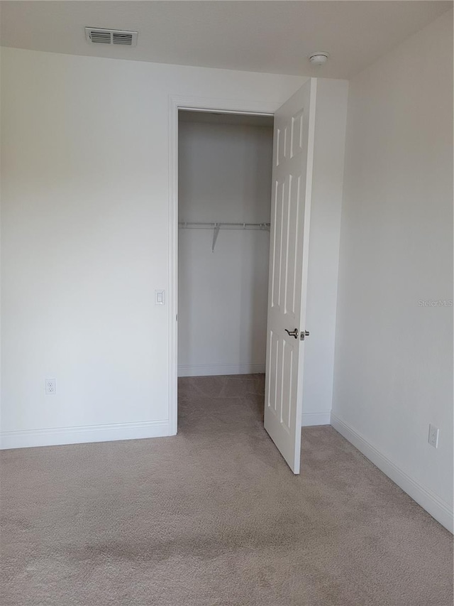 unfurnished bedroom with light carpet and a closet