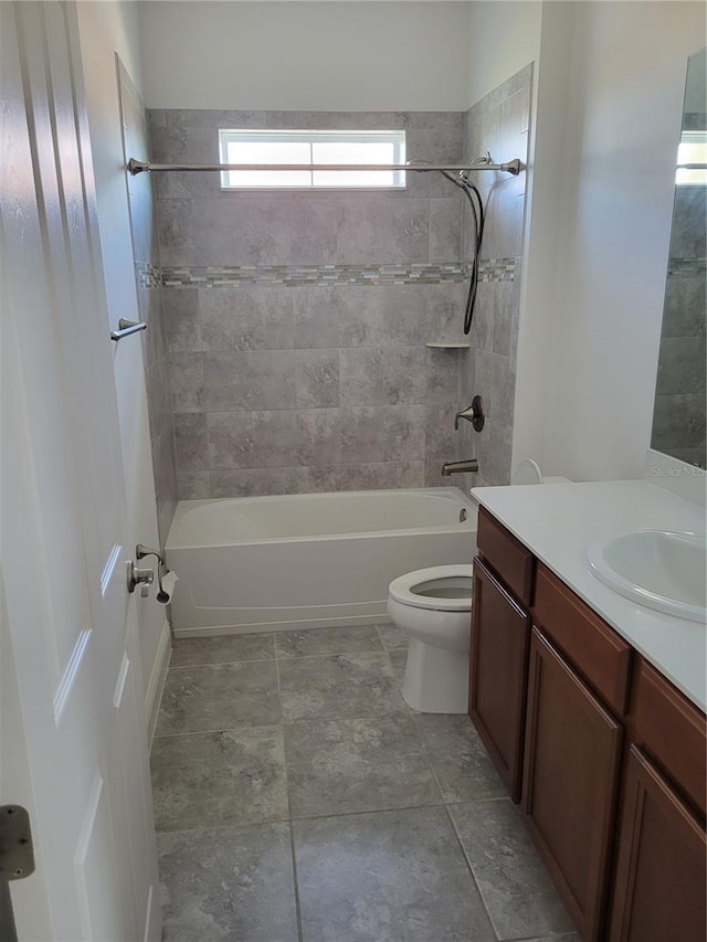 full bathroom featuring vanity, tiled shower / bath combo, and toilet