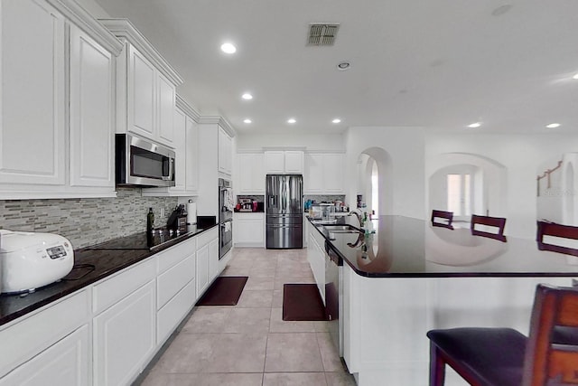 kitchen with stainless steel appliances, a center island with sink, sink, a breakfast bar area, and white cabinets