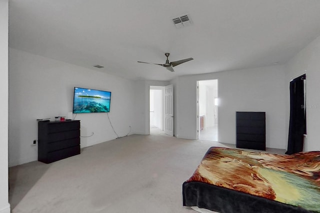 bedroom with light colored carpet, ceiling fan, and ensuite bath