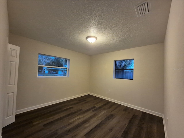 empty room featuring dark hardwood / wood-style flooring and a textured ceiling