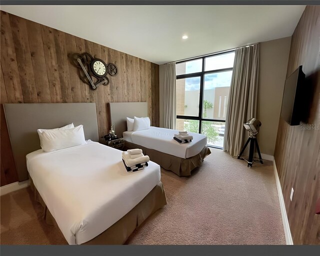 bedroom with wood walls, expansive windows, and light carpet