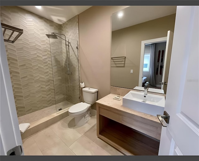 bathroom with vanity, toilet, tile patterned flooring, and tiled shower