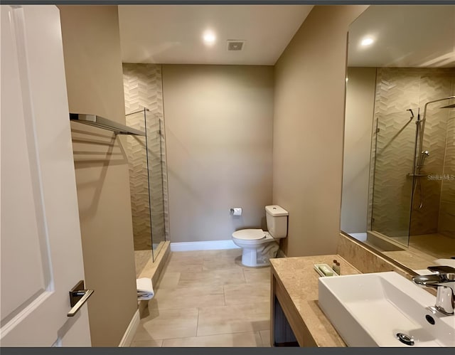 bathroom featuring tile patterned floors, vanity, tiled shower, and toilet