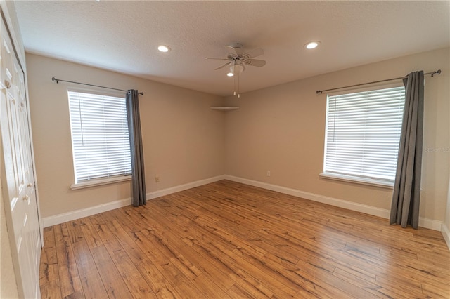 empty room featuring ceiling fan, light hardwood / wood-style floors, and a wealth of natural light