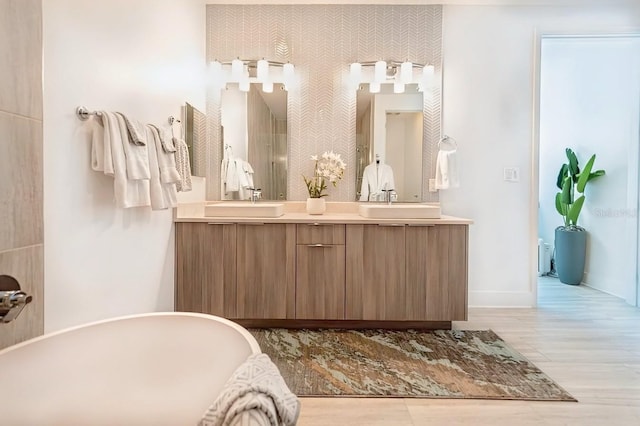 bathroom featuring wood-type flooring, vanity, and a tub to relax in