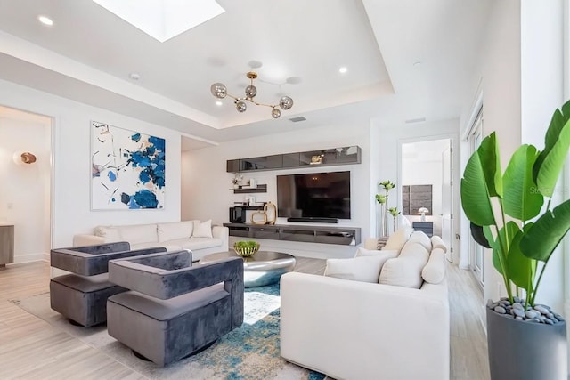 living room featuring light hardwood / wood-style floors, a raised ceiling, and a skylight