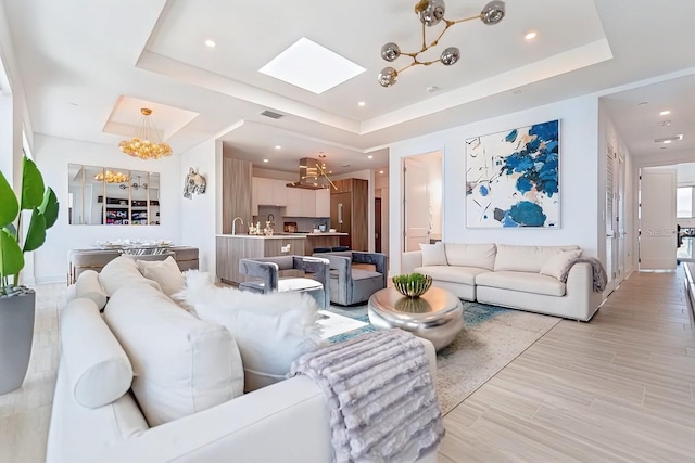 living room featuring a raised ceiling, light hardwood / wood-style floors, and a notable chandelier